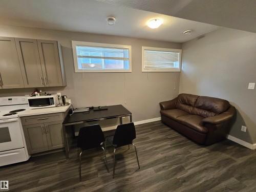 Compact kitchen area featuring gray cabinetry, white countertops, and a white electric range - 13309 104 Street Nw, Edmonton, AB - Indoor