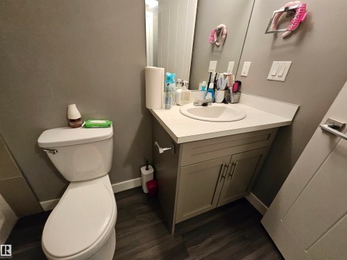 Bathroom vanity featuring an integrated sink, light countertop, and dual-door cabinetry with contemporary hardware - 13309 104 Street Nw, Edmonton, AB - Indoor Photo Showing Bathroom