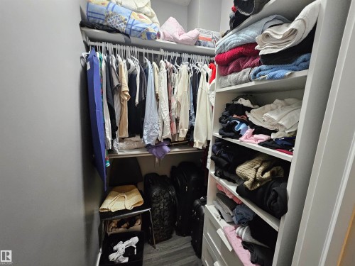 Built-in closet system featuring multiple hanging rods, white shelving, and lower drawers - 13309 104 Street Nw, Edmonton, AB - Indoor With Storage