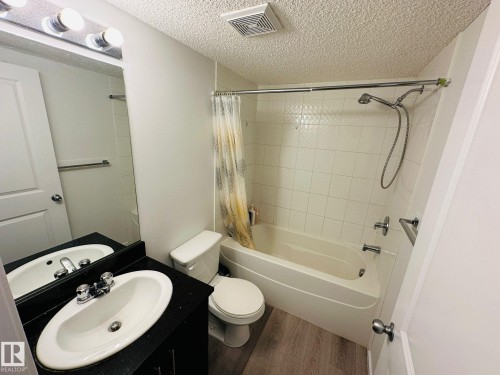 Full bathroom featuring a single vanity with a black countertop, oval undermount sink, and chrome fixtures - 1510 Watt Drive Southwest, Edmonton, AB - Indoor Photo Showing Bathroom