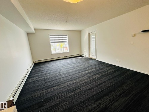 Spacious room featuring dark patterned carpeting and neutral white walls - 1510 Watt Drive Southwest, Edmonton, AB - Indoor Photo Showing Other Room