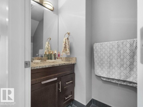 Vanity area featuring a granite countertop, undermount sink, and dark wood-finish cabinetry with brushed nickel hardware - 7909 105 Avenue Nw, Edmonton, AB - Indoor Photo Showing Bathroom