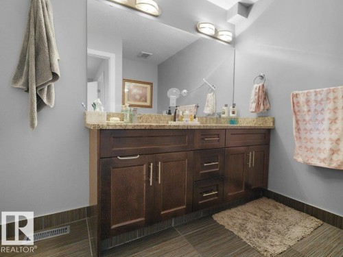 Vanity featuring a stone countertop, an integrated sink, and dark wood-finish cabinetry - 7909 105 Avenue Nw, Edmonton, AB - Indoor Photo Showing Bathroom