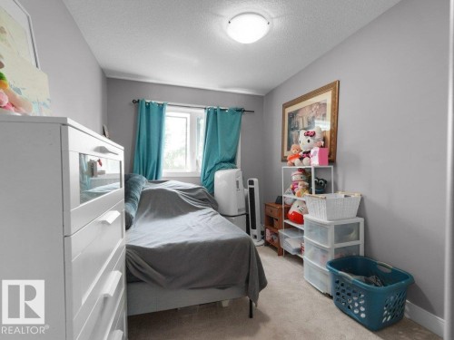 Light gray walls accentuating a window with teal curtains, complemented by a ceiling-mounted light fixture and carpeted flooring - 7909 105 Avenue Nw, Edmonton, AB - Indoor Photo Showing Bedroom