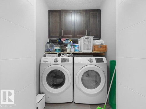 Dedicated laundry area featuring dark wood-finish cabinetry, a stone-finish countertop, and durable tile flooring - 7909 105 Avenue Nw, Edmonton, AB - Indoor Photo Showing Laundry Room