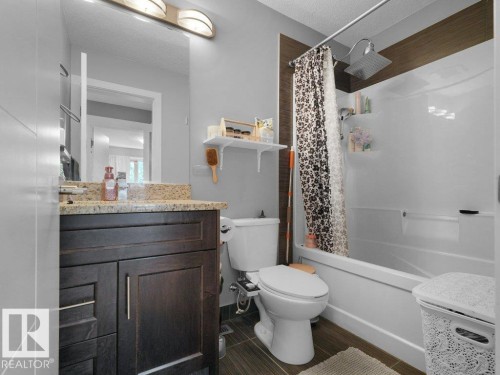 Bathroom featuring a dark wood-finish vanity with a stone countertop, a full-size mirror, and overhead vanity lighting - 7909 105 Avenue Nw, Edmonton, AB - Indoor Photo Showing Bathroom