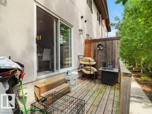 Private outdoor deck with wood decking, featuring a sliding glass door entry, exterior wall sconces, and a wood privacy fence - 7909 105 Avenue Nw, Edmonton, AB - Outdoor With Deck Patio Veranda With Exterior