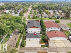 Charming residential property featuring a distinctive two-story design with a dark gray pitched roof, white exterior siding, and wood-finish accents - 