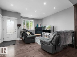 Living area featuring wood-finish flooring, recessed lighting, a white framed window with decorative curtains, and a white entry door with frosted glass panels - 
