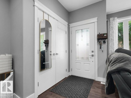 Entryway featuring a white paneled door with decorative glass inserts, dark wood-finish flooring, and white interior trim - 7909 105 Avenue Nw, Edmonton, AB - Indoor Photo Showing Other Room