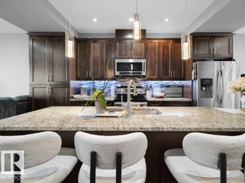 Kitchen featuring a spacious island with a light-toned granite countertop, undermount sink, and modern faucet - 7909 105 Avenue Nw, Edmonton, AB - Indoor Photo Showing Kitchen With Double Sink With Upgraded Kitchen