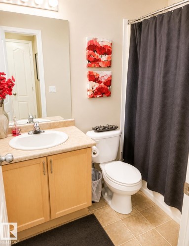 Full bathroom featuring a white toilet, light wood-finish vanity with an integrated sink, large wall-mounted mirror, and tile flooring - #202 16715 100 Av Nw, Edmonton, AB - Indoor Photo Showing Bathroom