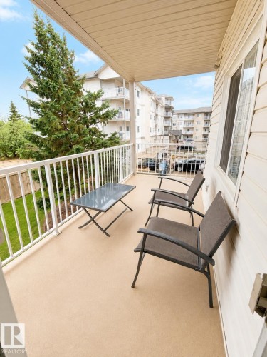 Outdoor balcony featuring a textured floor, white railing, and soffit ceiling - #202 16715 100 Av Nw, Edmonton, AB - Outdoor With Balcony With Exterior