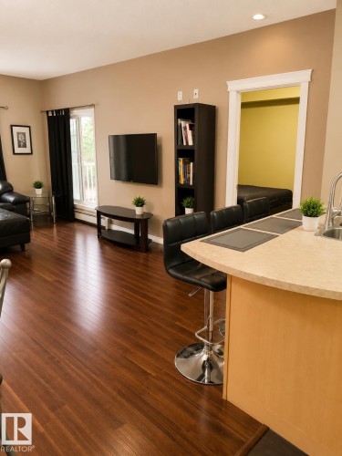 Open-concept living area featuring wood-finish flooring, recessed lighting, a neutral wall palette, and a kitchen island with a light-toned countertop - #202 16715 100 Av Nw, Edmonton, AB - Indoor Photo Showing Living Room