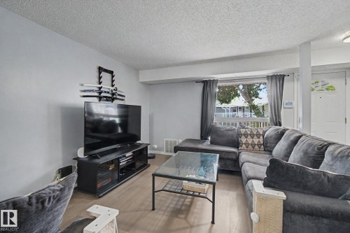 Living area featuring wood-finish flooring and a large window with exterior railing - #39 3111 142 Av Nw, Edmonton, AB - Indoor Photo Showing Living Room