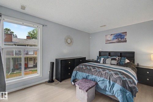 Bright interior space featuring light-toned wood-finish flooring, a large window, and light gray walls - #39 3111 142 Av Nw, Edmonton, AB - Indoor Photo Showing Bedroom