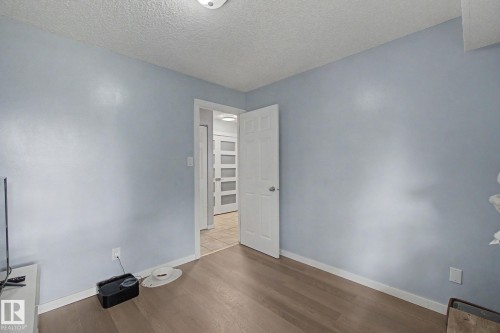 Light blue painted walls with wood-finish flooring, white trim, and a white ceiling - #39 3111 142 Av Nw, Edmonton, AB - Indoor Photo Showing Other Room