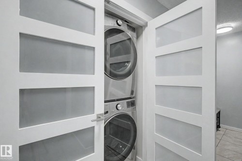 Modern laundry closet featuring a stacked washer and dryer unit - #39 3111 142 Av Nw, Edmonton, AB - Indoor Photo Showing Laundry Room