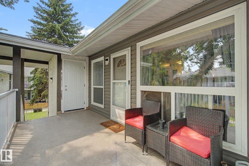 Covered concrete patio featuring dark gray horizontal siding and a large picture window - #39 3111 142 Av Nw, Edmonton, AB - Outdoor With Deck Patio Veranda With Exterior
