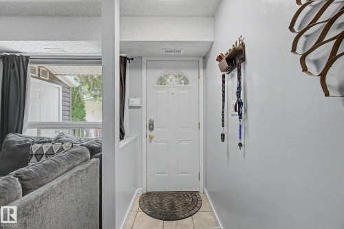 Entryway featuring a white door with an arched glass insert, light-toned tile flooring, and light gray wall finishes - #39 3111 142 Av Nw, Edmonton, AB - Indoor Photo Showing Other Room