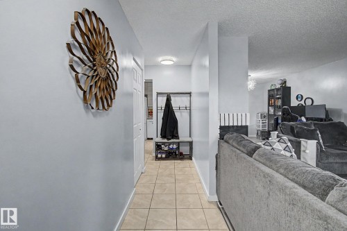 Hallway featuring tile flooring, a flush-mount ceiling light, and a white paneled door - #39 3111 142 Av Nw, Edmonton, AB - Indoor