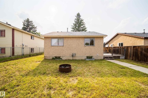Rear exterior featuring stucco finish, two windows, and a concrete walkway - 1719 37 Street Nw, Edmonton, AB - Outdoor With Exterior