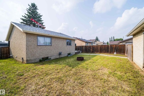 Expansive backyard featuring a full perimeter wood fence, a concrete patio area, and mature landscaping - 1719 37 Street Nw, Edmonton, AB - Outdoor