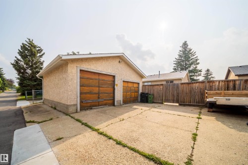 Detached two-car garage with textured stucco exterior and dual wooden overhead doors - 1719 37 Street Nw, Edmonton, AB - Outdoor With Exterior