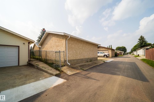 Detached garage with white overhead door, concrete driveway, and cream-colored siding - 1719 37 Street Nw, Edmonton, AB - Outdoor With Exterior