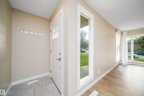 Entryway featuring a white paneled front door with clear glass inserts, a vertical side window, and light-toned walls - 1719 37 Street Nw, Edmonton, AB - Indoor Photo Showing Other Room