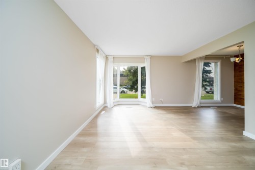 Bright living area featuring light wood-finish flooring, neutral wall tones, and multiple large windows - 1719 37 Street Nw, Edmonton, AB - Indoor