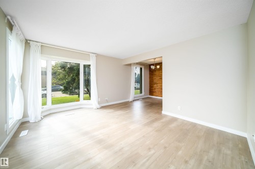 Spacious room featuring light wood-finish flooring, a large bay window, and white trim - 1719 37 Street Nw, Edmonton, AB - Indoor