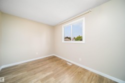 Neutral wall paint, wood-finish flooring, white baseboards, and a white-framed window - 