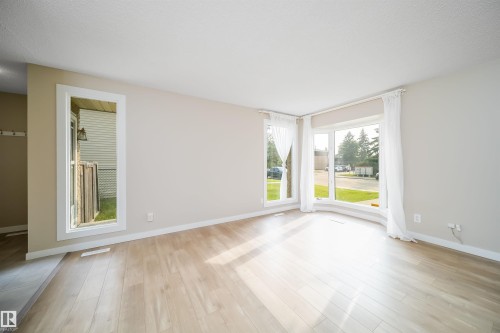 Bright living space featuring a bay window, wood-finish flooring, neutral wall paint, and white trim - 1719 37 Street Nw, Edmonton, AB - Indoor Photo Showing Other Room
