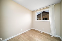 Neutral-toned room featuring light wood-finish flooring, white baseboards, and a window with white trim - 