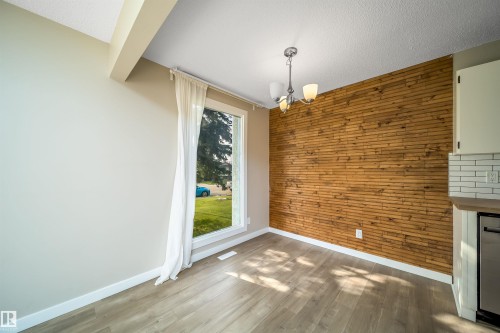 Accent wall with horizontal wood paneling, wood-finish flooring, and a multi-bulb ceiling fixture - 1719 37 Street Nw, Edmonton, AB - Indoor Photo Showing Other Room