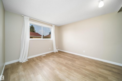 Room featuring a large horizontal window, wood-finish flooring, light neutral wall paint, and white trim - 1719 37 Street Nw, Edmonton, AB - Indoor Photo Showing Other Room