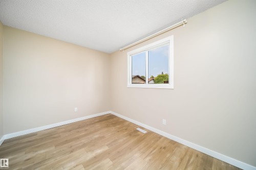 Neutral wall paint, wood-finish flooring, white baseboards, and a white-framed window - 1719 37 Street Nw, Edmonton, AB - Indoor Photo Showing Other Room