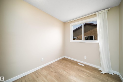Neutral-toned room featuring light wood-finish flooring, white baseboards, and a window with white trim - 1719 37 Street Nw, Edmonton, AB - Indoor Photo Showing Other Room