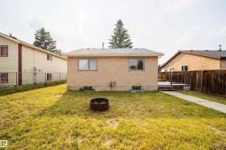 Rear exterior featuring stucco finish, two windows, and a concrete walkway - 