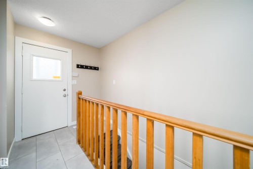 Entryway featuring a white door with an integrated window, overhead flush-mount lighting, a built-in coat rack, and light grey tiled flooring - 1719 37 Street Nw, Edmonton, AB - Indoor Photo Showing Other Room