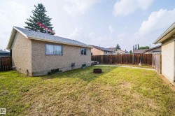Expansive backyard featuring a full perimeter wood fence, a concrete patio area, and mature landscaping - 
