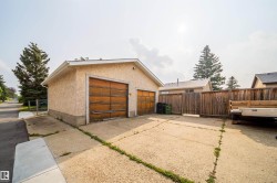 Detached two-car garage with textured stucco exterior and dual wooden overhead doors - 