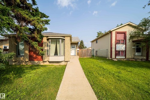 Exterior featuring a bay window, stucco finish, and a concrete pathway leading to the front entry - 1719 37 Street Nw, Edmonton, AB - Outdoor