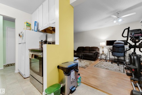 Compact kitchen featuring white cabinetry and a stainless steel range - #104 11445 41 Av Nw, Edmonton, AB - Indoor