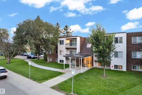 Multi-story building featuring a pitched shingle roof and a combination of white siding and dark brick exterior - #104 11445 41 Av Nw, Edmonton, AB - Outdoor With Facade