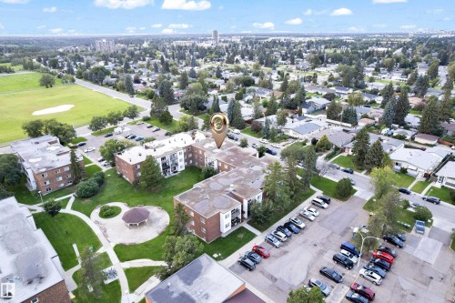 Multi-story apartment building featuring brick and white siding, surrounded by mature trees - #104 11445 41 Av Nw, Edmonton, AB - Outdoor With View