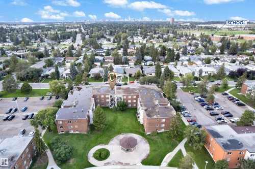 Aerial perspective showcasing a multi-building complex with brick exteriors and surrounding green spaces - #104 11445 41 Av Nw, Edmonton, AB - Outdoor With View