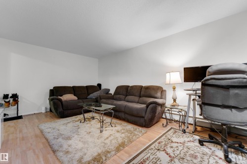 Spacious room featuring light wood-finish flooring, white walls, and a textured ceiling - #104 11445 41 Av Nw, Edmonton, AB - Indoor Photo Showing Living Room