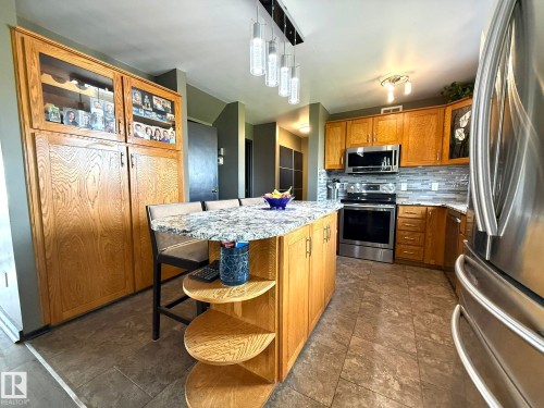 Kitchen featuring a central island with a stone-finish countertop and integrated seating - 4508 57 Avenue, Lamont, AB - Indoor Photo Showing Kitchen